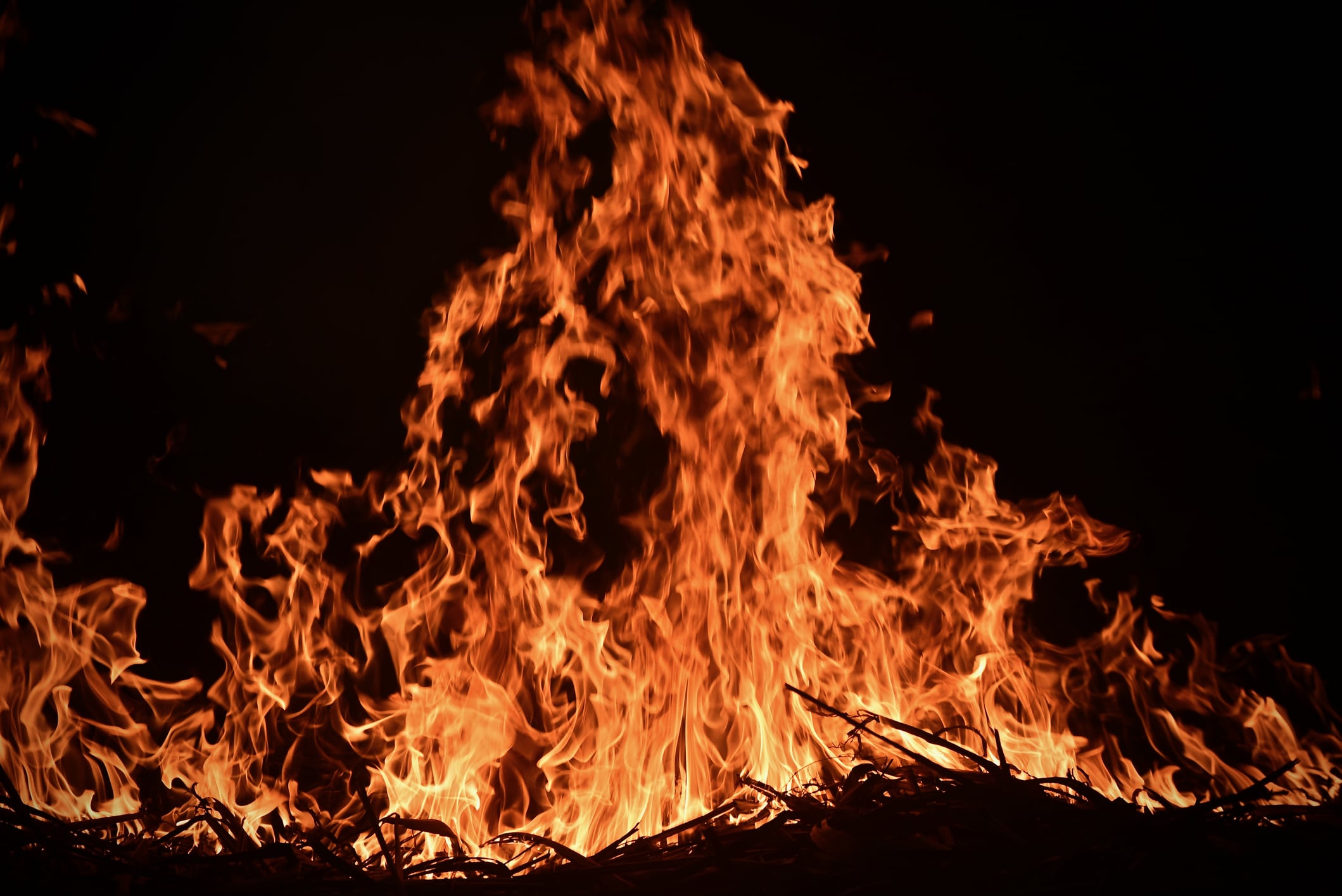 Trash fire in darkness with orange flames climbing up the entire photo